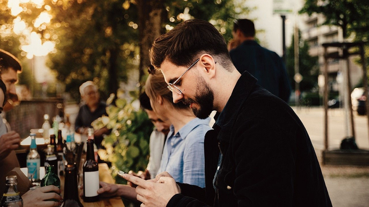 Man at an outdoor dining table using his phone