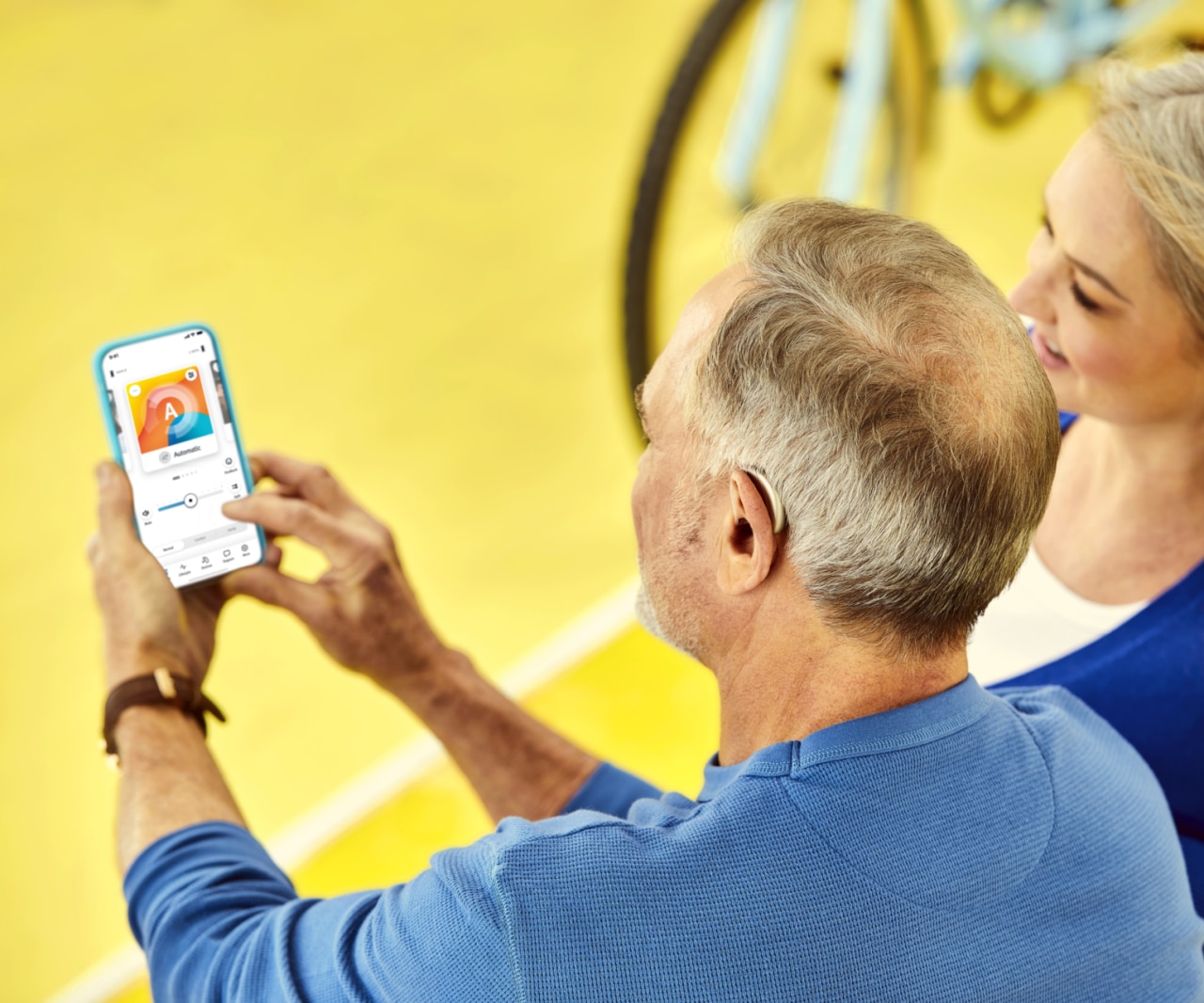 A man holding a mobile phone, setting up his hearing aids via remote app