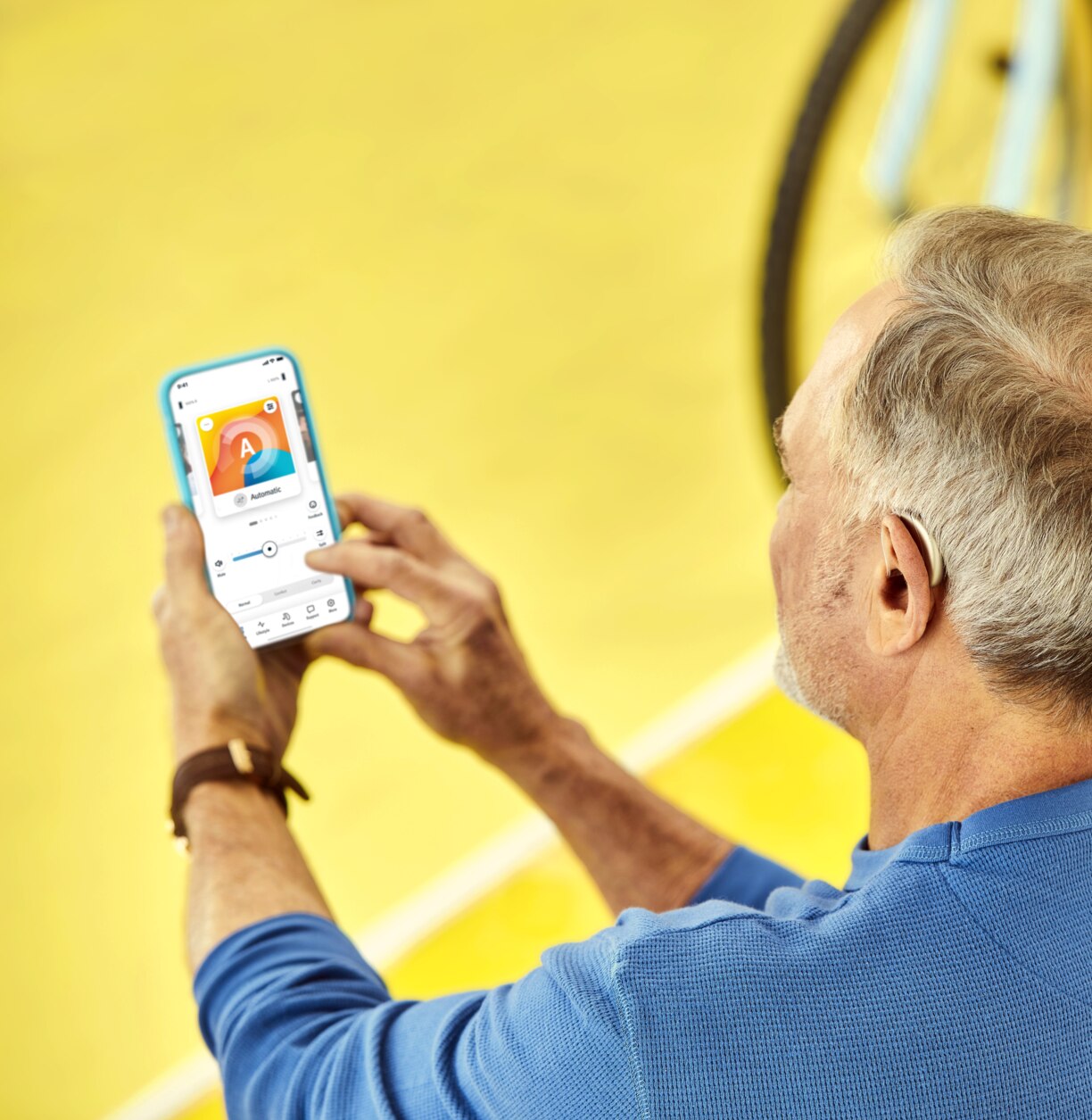 A man holding a mobile phone, setting up his hearing aids via remote app