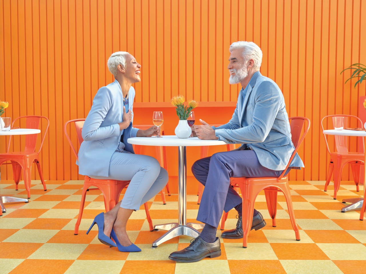 Un couple élégant est assis à une petite table ronde dans un café animé.
