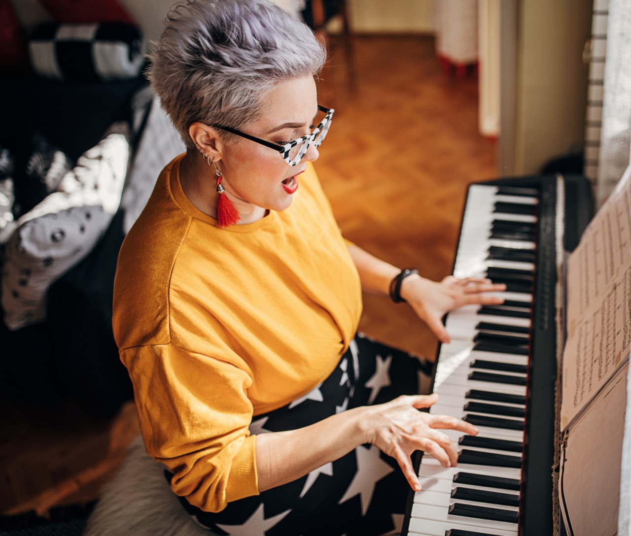 One young woman, composer, playing synthesizer and singing in living room at home.