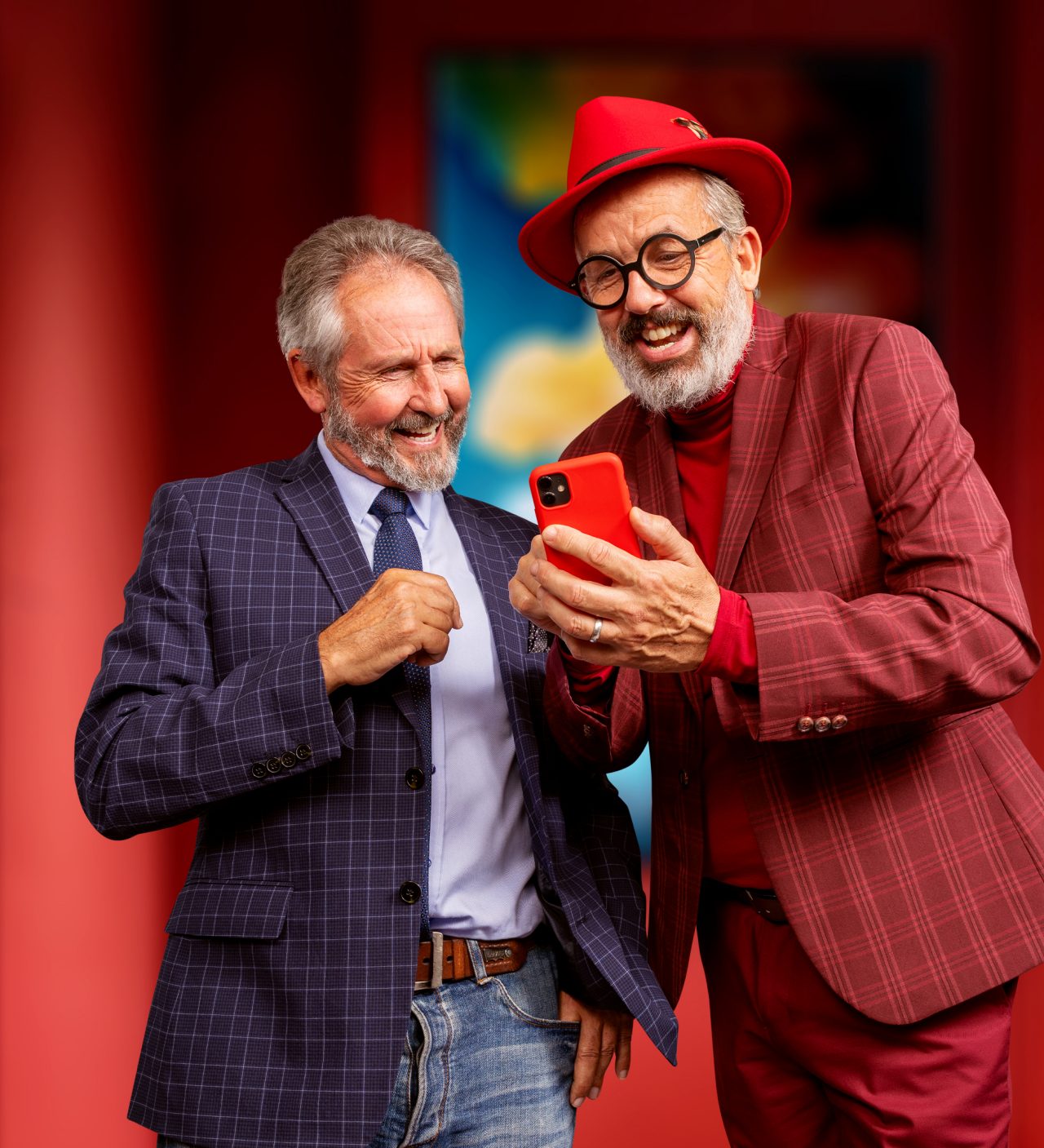 Twee oudere mannen delen een moment, glimlachend terwijl ze naar een smartphonescherm kijken.