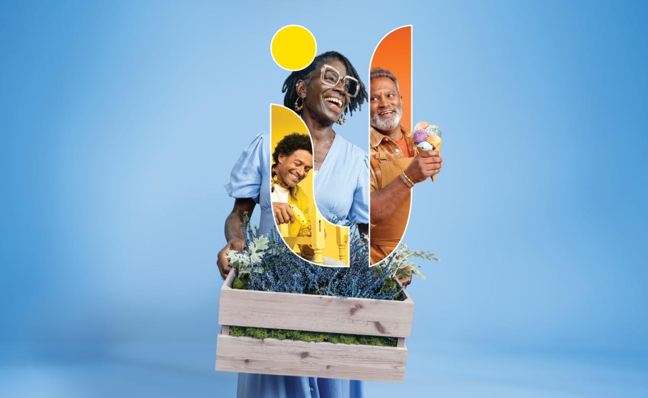 Een persoon houdt een houten krat vast met meerdere kleurrijke vormen en afbeeldingen, waardoor een collage van mensen en natuur wordt gemaakt tegen een lichtblauwe achtergrond.