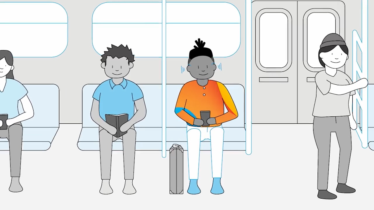 Duas pessoas sentadas em um vagão de metrô, uma delas está lendo um livro e a outra está usando um smartphone, enquanto uma terceira pessoa está de pé ao lado da porta, segurando na barra de apoio
