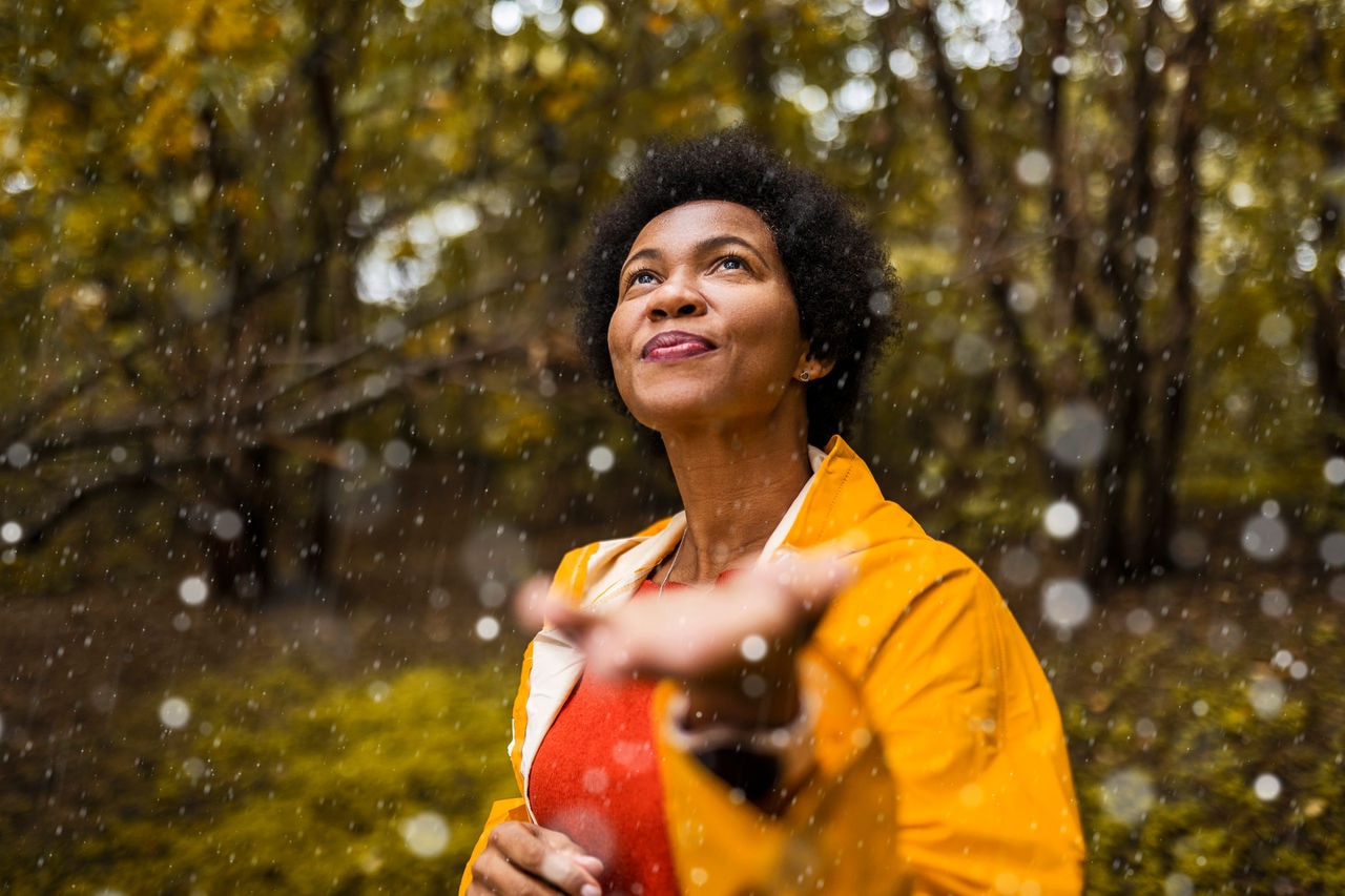 Mulher afro-americana vestindo capa de chuva amarela em um dia chuvoso