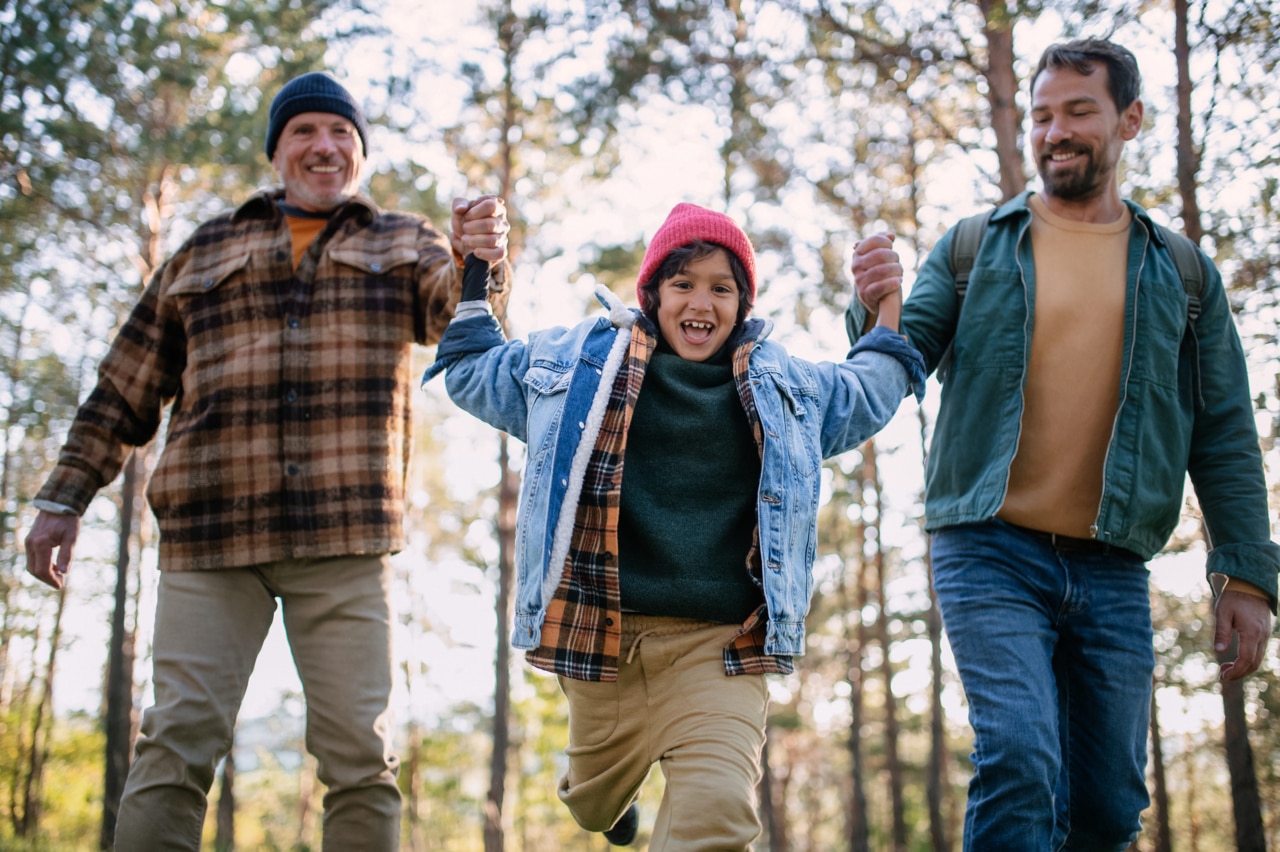 Três gerações de homens caminhando na floresta, explorando a natureza juntos.