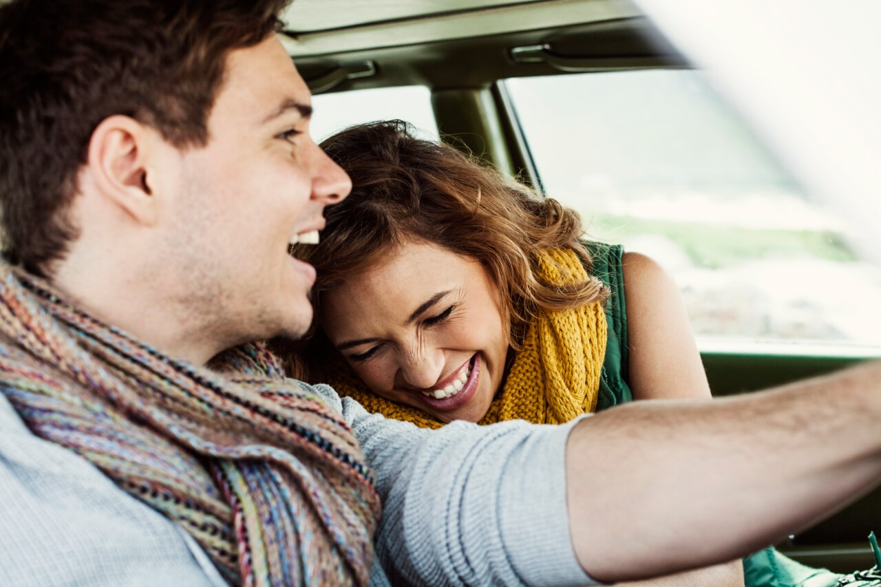  Two individuals sitting inside a car, with one person resting their head on the other's shoulder. The atmosphere appears cozy and intimate, suggesting a moment of comfort and connection between them. The interior of the car is well-lit, and the scenery outside the window hints at a beautiful landscape