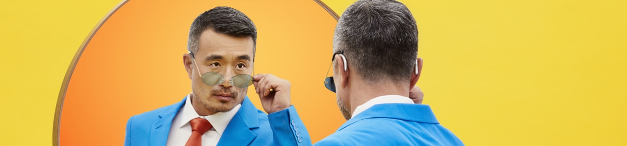 A man looks at a small mirror placed above sunglasses