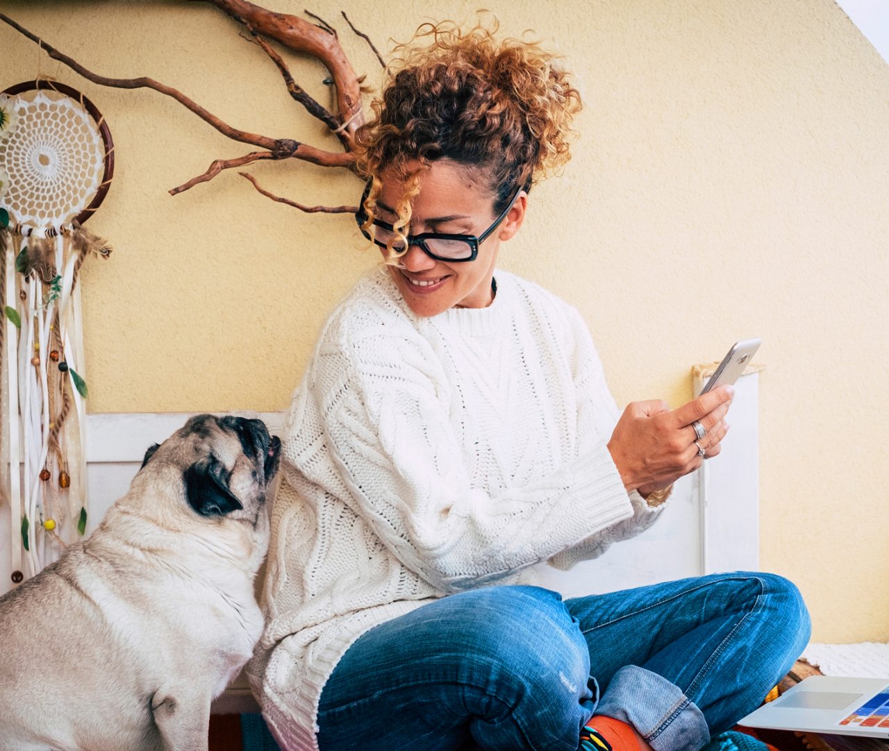 Woman and her lovely pug dog sit down at home while work with technology devices like phone and laptop