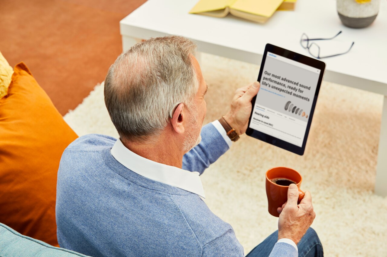 Un homme assis lisant un guide d’utilisation affiché sur une tablette.
