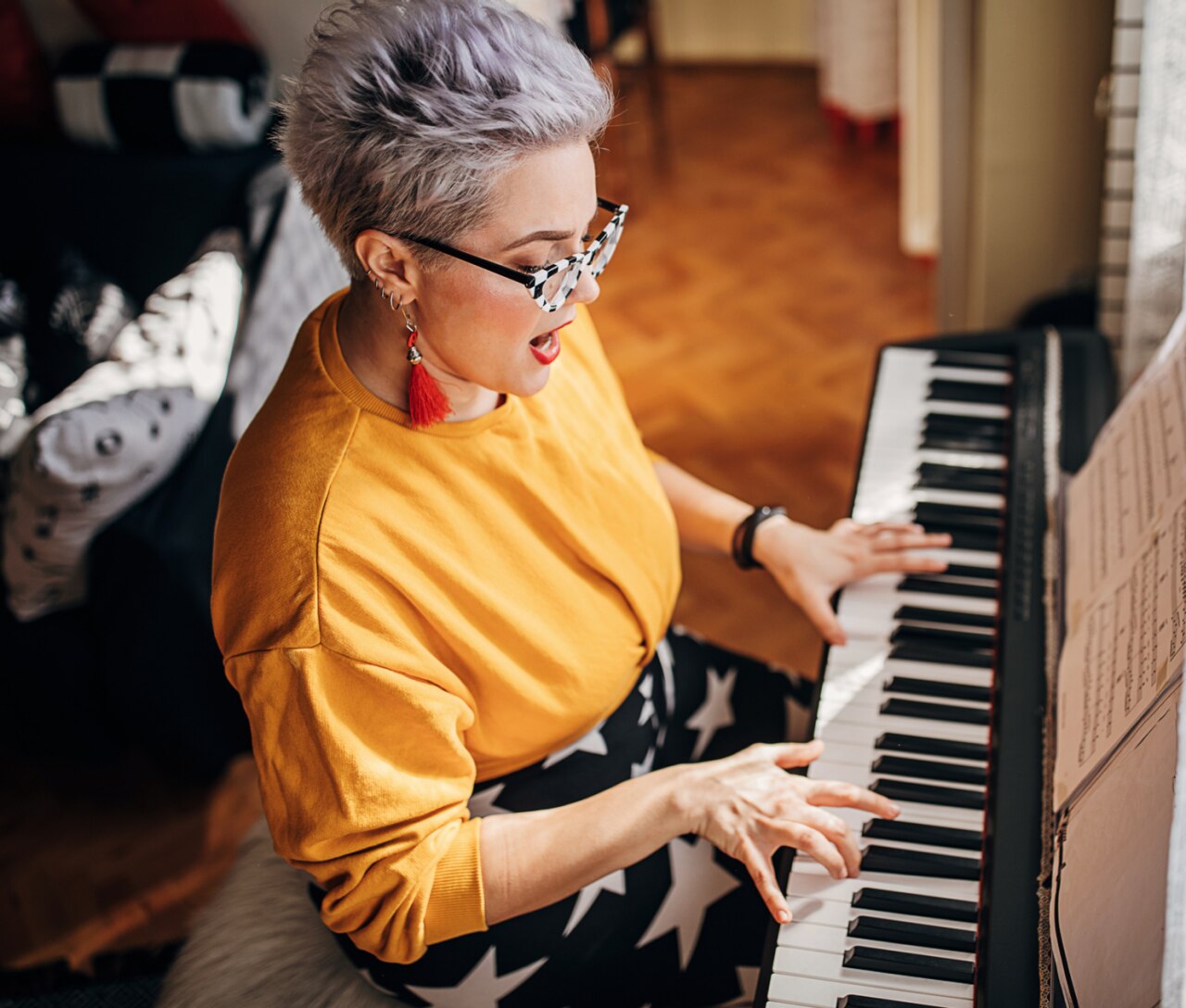 One young woman, composer, playing synthesizer and singing in living room at home.