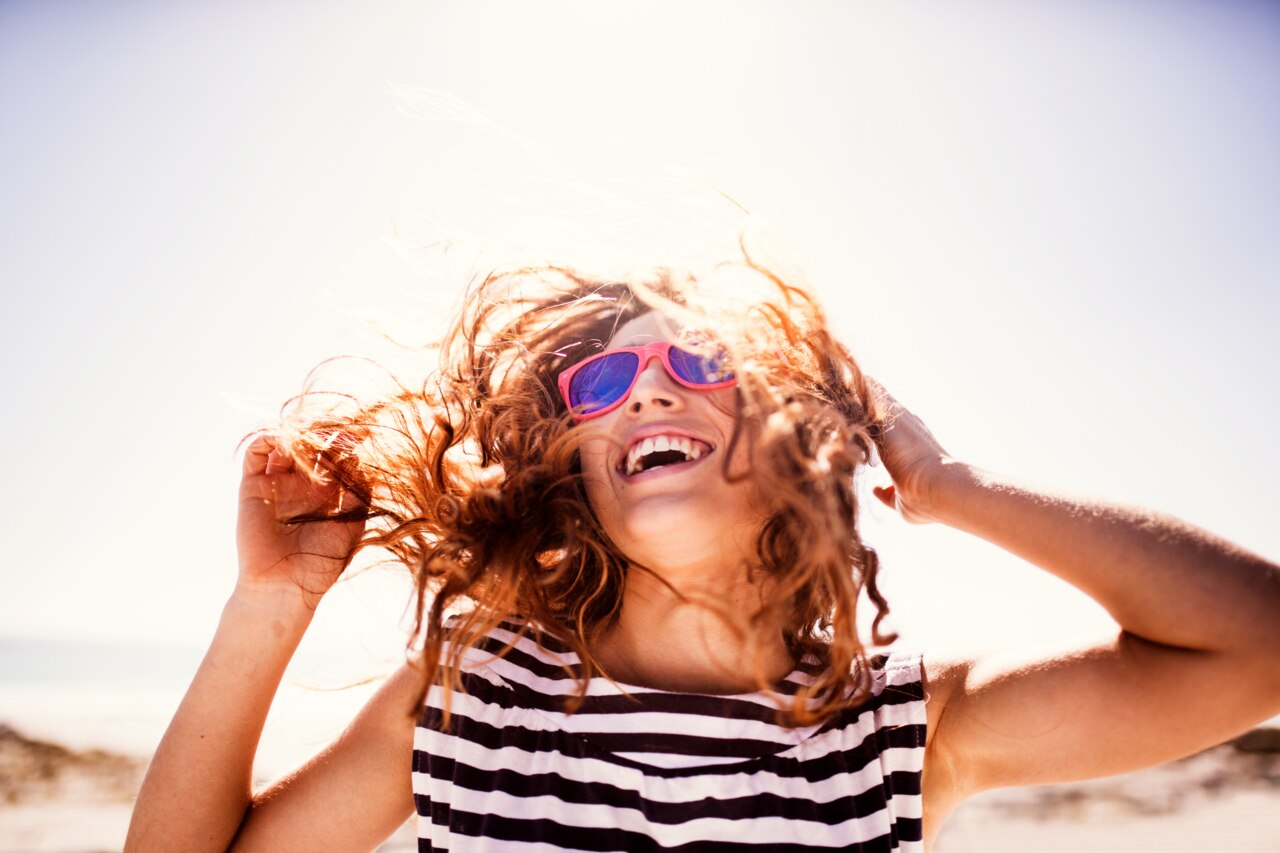 Cheerful laughing teenage girl during summer holiday on the beach
