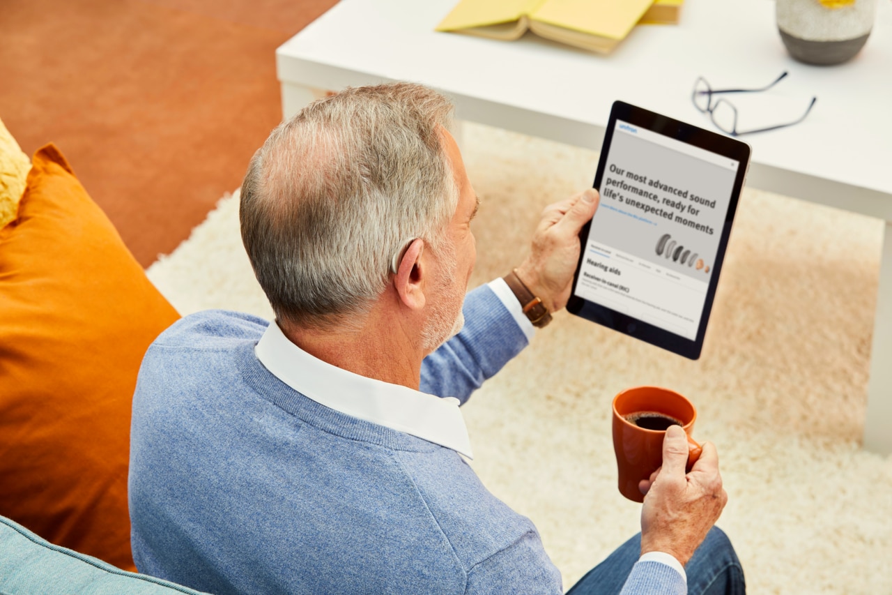 A man sits and reads a user guide displayed on a tablet.
