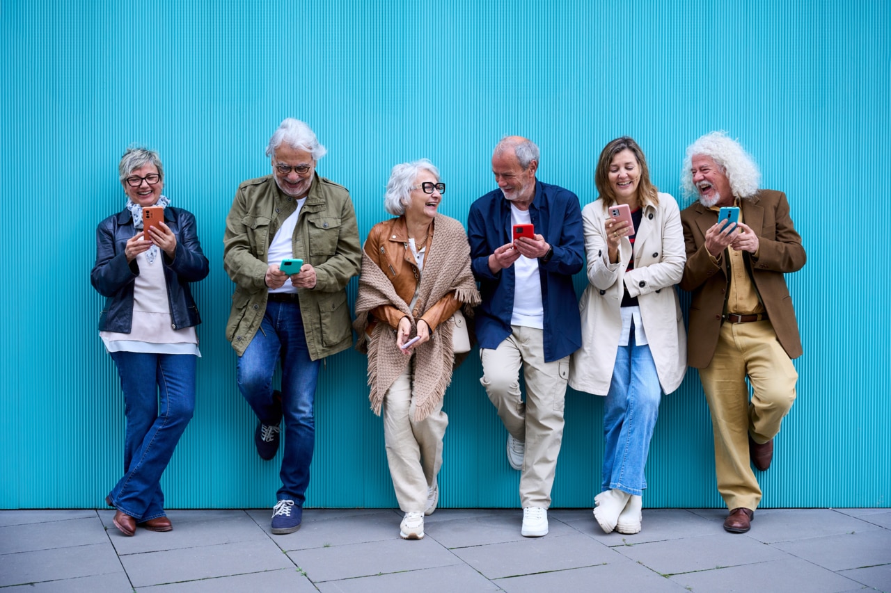 A group of elderly people is seen enjoying themselves with a game of cards.