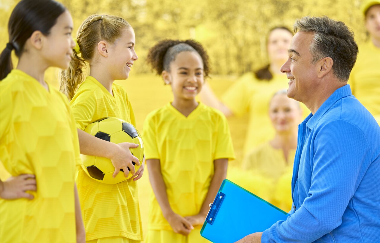 Coach talking with youth soccer players on the sideline, illustrating clear conversations in noisy environments